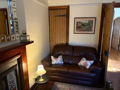 a brown leather couch in a living room with a fireplace at 11 George Street Doune in Stirling