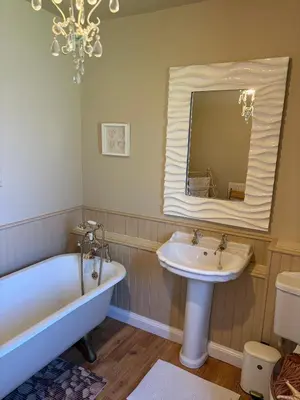 a bathroom with a tub and a sink and a mirror at 11 George Street Doune in Stirling