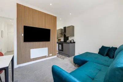 a living room with a blue couch and a flat screen tv at George St Getaway in Ayr