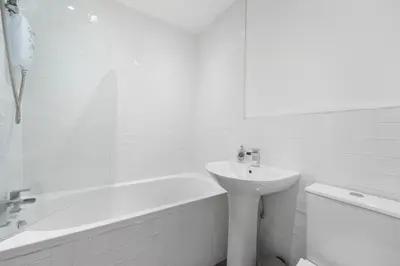 a white bathroom with a sink and a bath tub at George St Getaway in Ayr