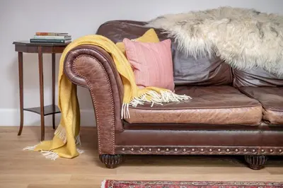 a brown couch with two pillows on it with a table at Burnside - gorgeous romantic cottage for 2 in Monzie