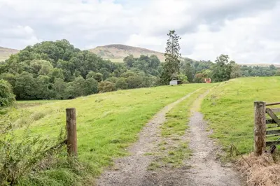 a dirt road in a field with a fence at Burnside - gorgeous romantic cottage for 2 in Monzie