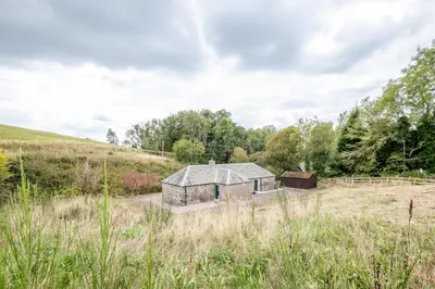 an old stone house in a field with trees at Burnside - gorgeous romantic cottage for 2 in Monzie