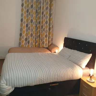 a bedroom with a bed and a window with curtains at Newly Furnished Flat 4 Minutes Walk To Metro in Glasgow