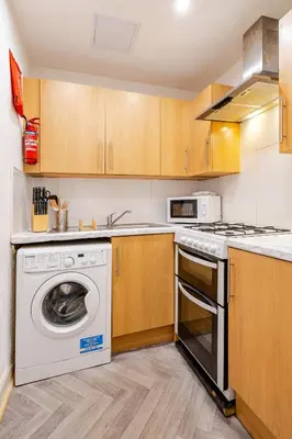 a kitchen with a washing machine and a stove at Newly Furnished Flat 4 Minutes Walk To Metro in Glasgow