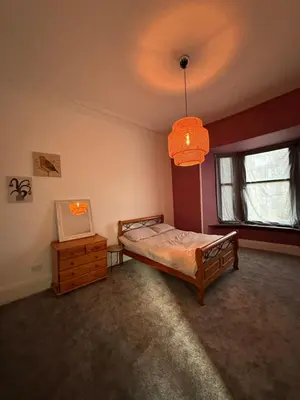 a bedroom with a bed and a window and a chandelier at Spacious 5 Bedroom House Close to Central West End in Glasgow