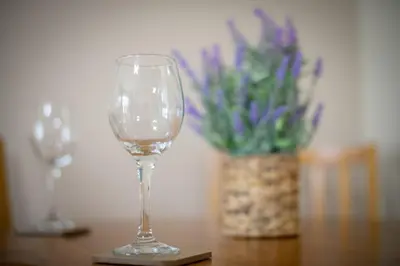 a wine glass sitting on a table with a vase of flowers at Charming 2 Bed Apartment in the heart of the West End in Glasgow
