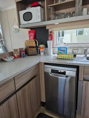 a kitchen with a counter with a dishwasher at Barbara's Caravan Craig Tara in Ayr