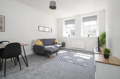 a living room with a couch and a table at Tobago Urban Apartment in Greenock