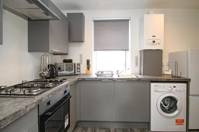 a kitchen with a stove and a washing machine at Tobago Urban Apartment in Greenock