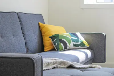 a blue couch with two pillows on it at Tobago Urban Apartment in Greenock