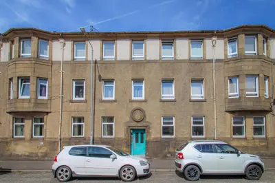 two cars parked in front of a brick building at Tobago Urban Apartment in Greenock