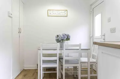 a white dining room with a table and chairs at 2 BDR House By Caledonia Luxe Stays Short Lets & Serviced Accommodation Glasgow in Glasgow