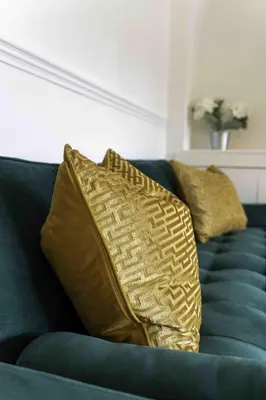 a blue couch with two gold pillows on it at 2 BDR House By Caledonia Luxe Stays Short Lets & Serviced Accommodation Glasgow in Glasgow