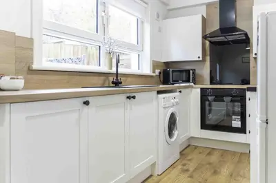a kitchen with white cabinets and a washer and dryer at 2 BDR House By Caledonia Luxe Stays Short Lets & Serviced Accommodation Glasgow in Glasgow