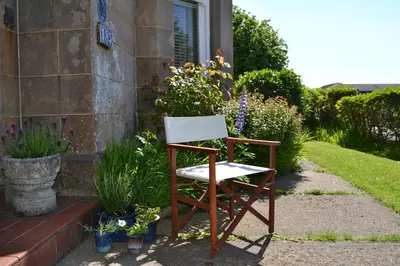 a chair sitting outside of a house with flowers at Maybank Guest House in Helensburgh