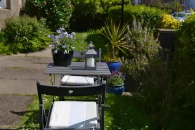 a table and chairs in a garden with potted plants at Maybank Guest House in Helensburgh