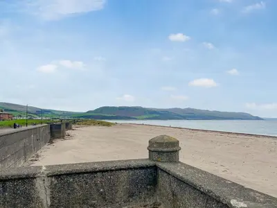 a beach with a retaining wall and the ocean at Beachcomber Apartment in Girvan
