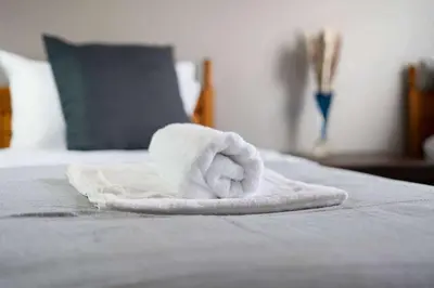 a white towel sitting on top of a bed at 2-Bed Flat Wishaw Free Parking Family-Friendly in Wishaw