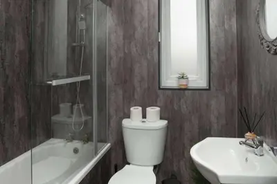 a bathroom with a toilet and a sink and a mirror at 2-Bed Flat Wishaw Free Parking Family-Friendly in Wishaw