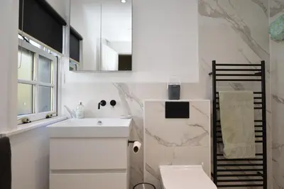 a white bathroom with a sink and a mirror at Old Powdermill Cottage in Tighnabruaich