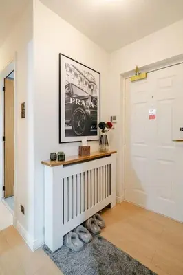 a hallway with a white door and a table with flowers at The Pad in Paisley