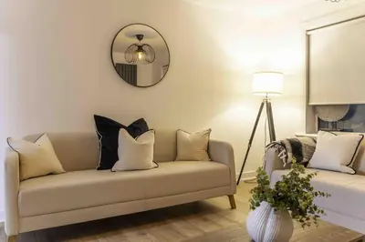a living room with a couch with pillows and a mirror at Montgomery Avenue in Paisley