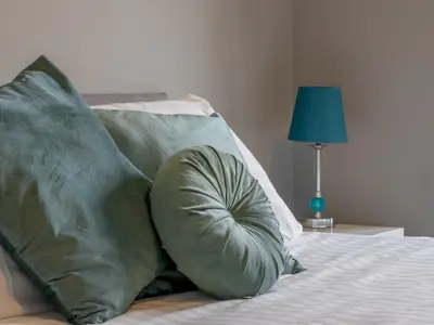 a bed with two green pillows and a blue lamp at Wonderful West End - Pass the Keys in Glasgow