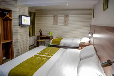 a hotel room with two beds and a television at Helix Hotel in Grangemouth