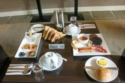 a table topped with plates of breakfast foods and coffee at Helix Hotel in Grangemouth