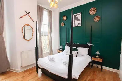 a bedroom with a green accent wall and a bed at Lovely spacious 2 Bed Flat in Glasgow