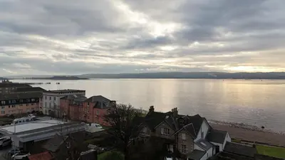 a view of a large body of water with buildings at 175 On Clyde - Spacious & Cosy Cedar Wood Bungalow in Helensburgh