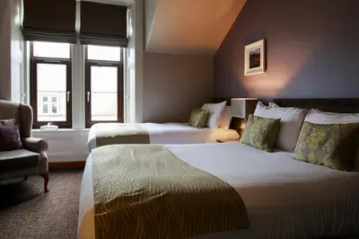 a hotel room with two beds and a chair at Angels Hotel in Uddingston
