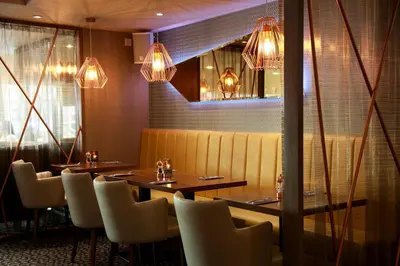 a dining room with tables and chairs and lights at Angels Hotel in Uddingston