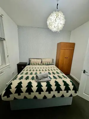 a bedroom with a bed with a blanket with trees on it at Blue Heaven Apartments in Edinburgh