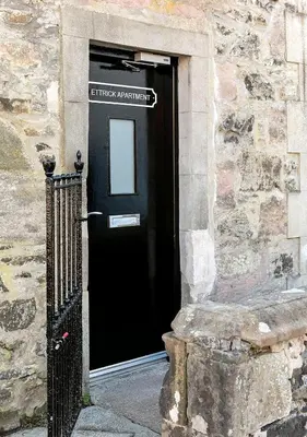 a black door of a stone building with a sign on it at Castle Street Apartments - Luxury Ettrick Apartment in Rothesay