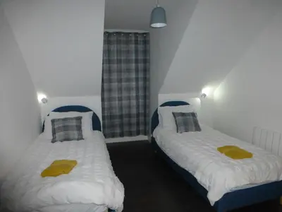 two beds in a small room with yellow towels on them at Quiet Street's Flat with free Parking near Town Centre in Largs