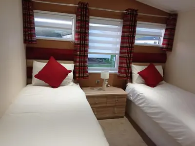 two beds in a room with two windows at Muirfield cosy retreat in Girvan