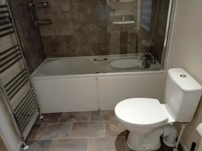 a bathroom with a toilet and a shower and a tub at Muirfield cosy retreat in Girvan