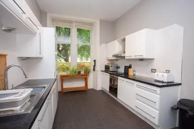 a kitchen with white cabinets and a large window at Lovely Flat in Ideal Location in Glasgow