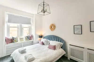 a bedroom with a bed and two windows at Boutique West End Apartment - 'The Nook' in Glasgow