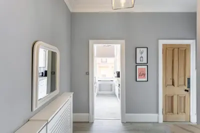 a white hallway with a mirror and a door at Boutique West End Apartment - 'The Nook' in Glasgow