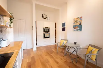 a kitchen with a table and a clock on the wall at Stunning 3 Bed Flat in the Heart of the West End in Glasgow