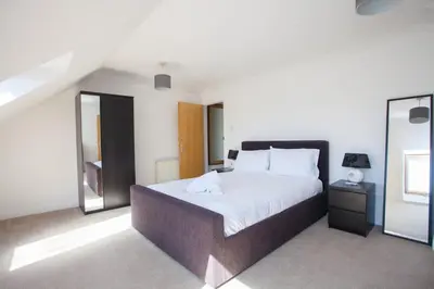 a bedroom with a large bed and a mirror at 3 Bedroom Duplex with Free Parking in Glasgow
