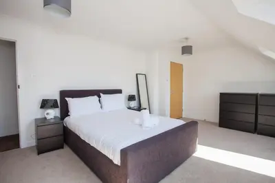 a bedroom with a large bed with white sheets at 3 Bedroom Duplex with Free Parking in Glasgow