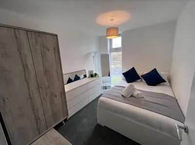a bedroom with a bed and a large wooden cabinet at Stylish Newly Decorated 2 Bed in Glasgow