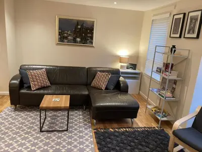 a living room with a black leather couch and a table at The Art Flat Woodlands in Glasgow