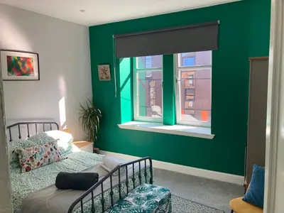 a bedroom with green walls and a bed and a window at 2 Bedroom Oasis in Glasgow City Centre in Glasgow