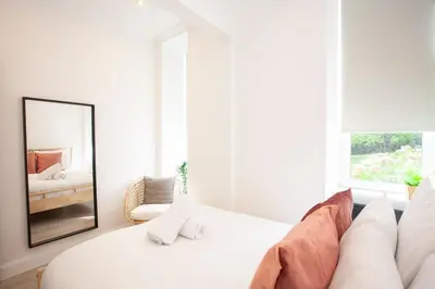 a white living room with a couch and a mirror at Stunning Flat in West End Location in Glasgow