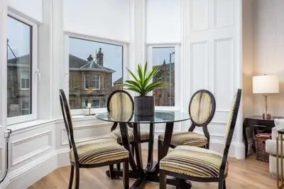 a dining room with a table and chairs and windows at The Bradshaw in Prestwick